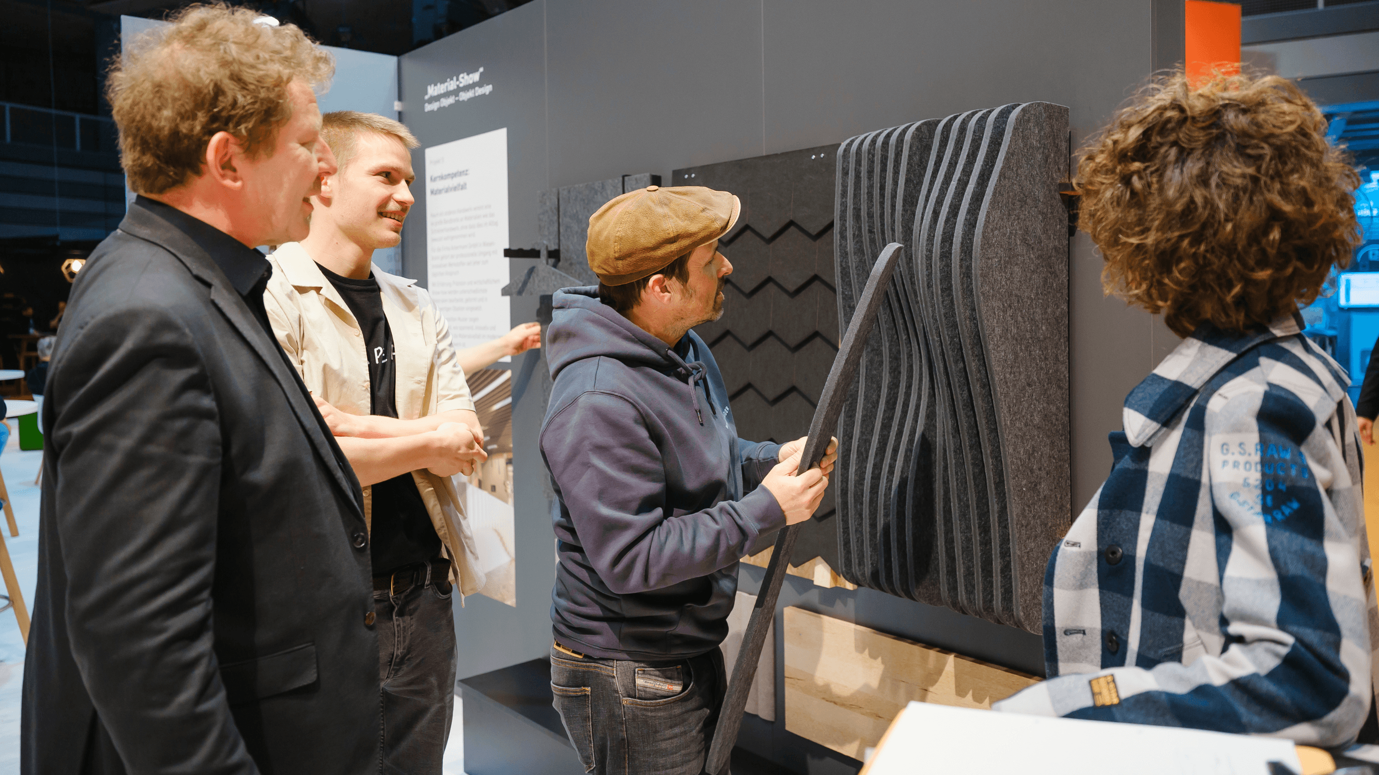 Three people examining and discussing material samples at an exhibition booth