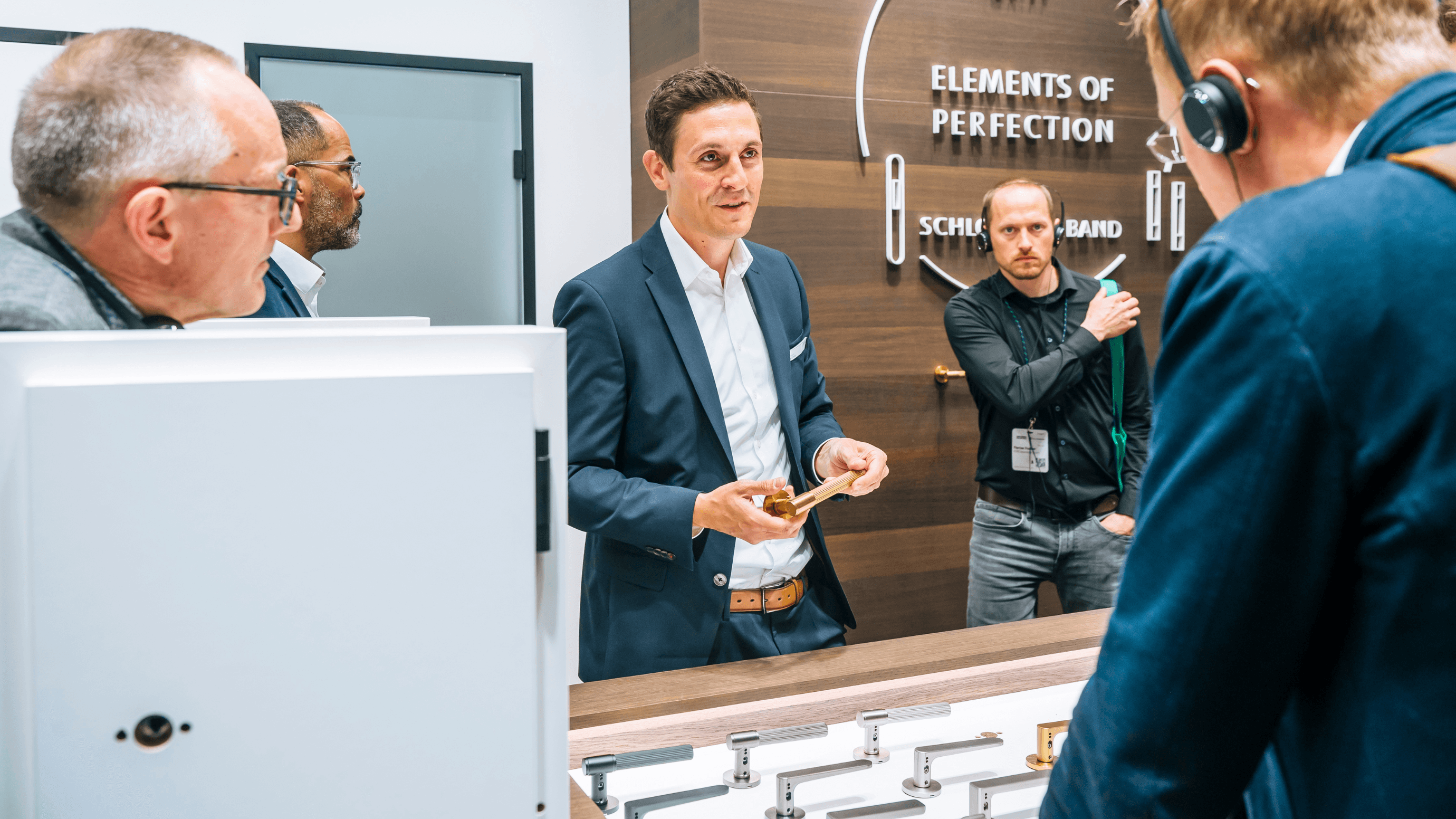Three people in conversation at an exhibition booth in a modern indoor setting